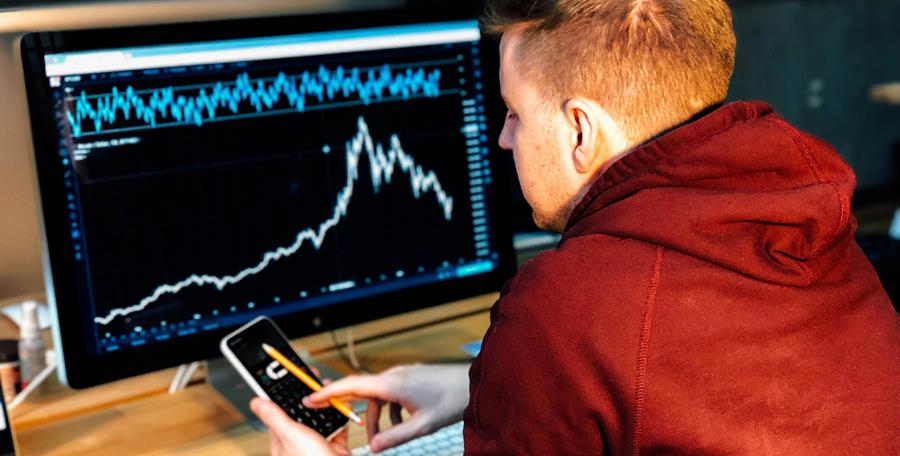 man sitting in front of a computer screen showing a graph.