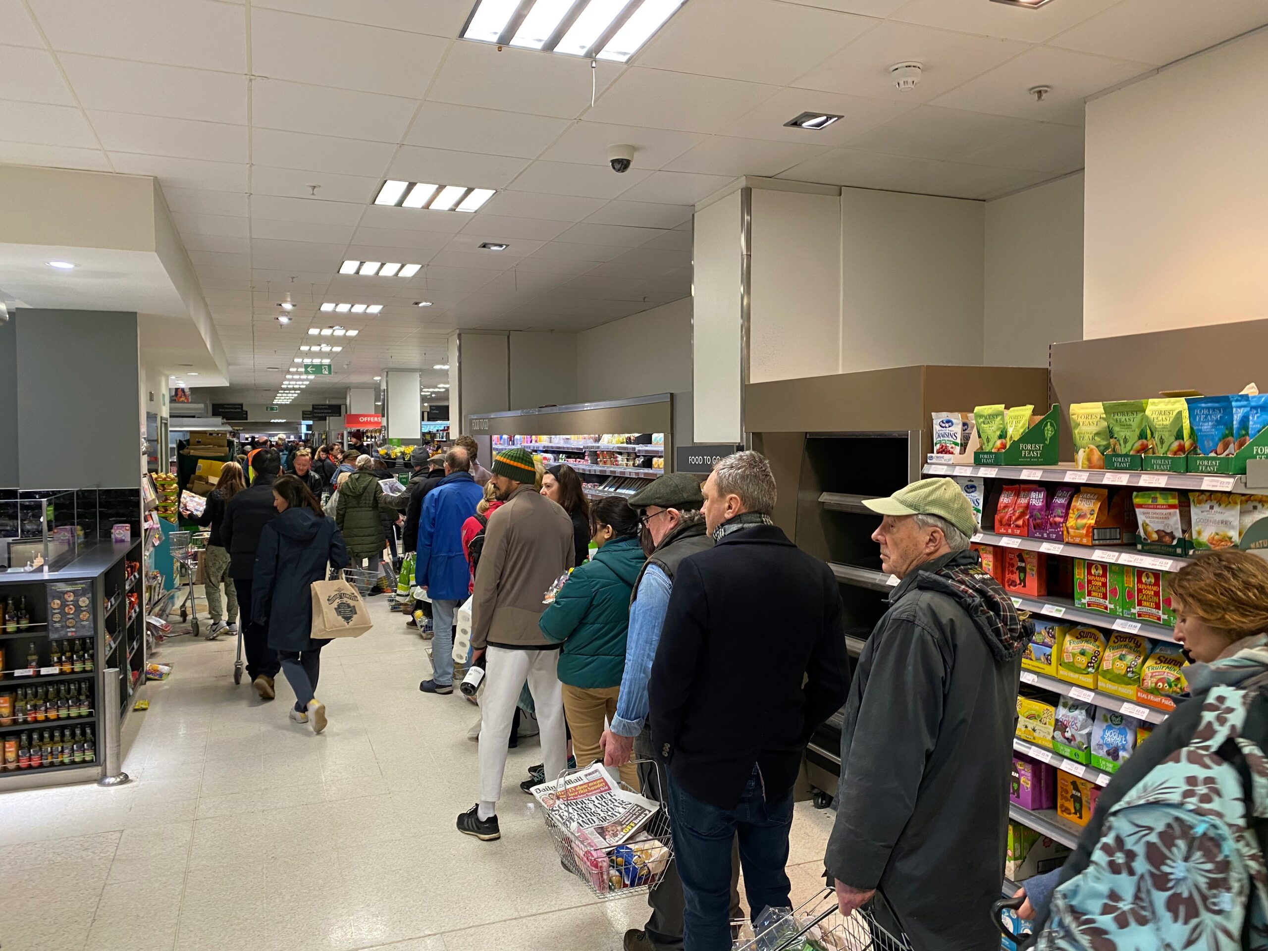 Queue of people down a supermarket aisle